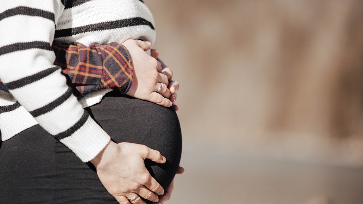 A pregnant woman in a striped shirt and black pants
